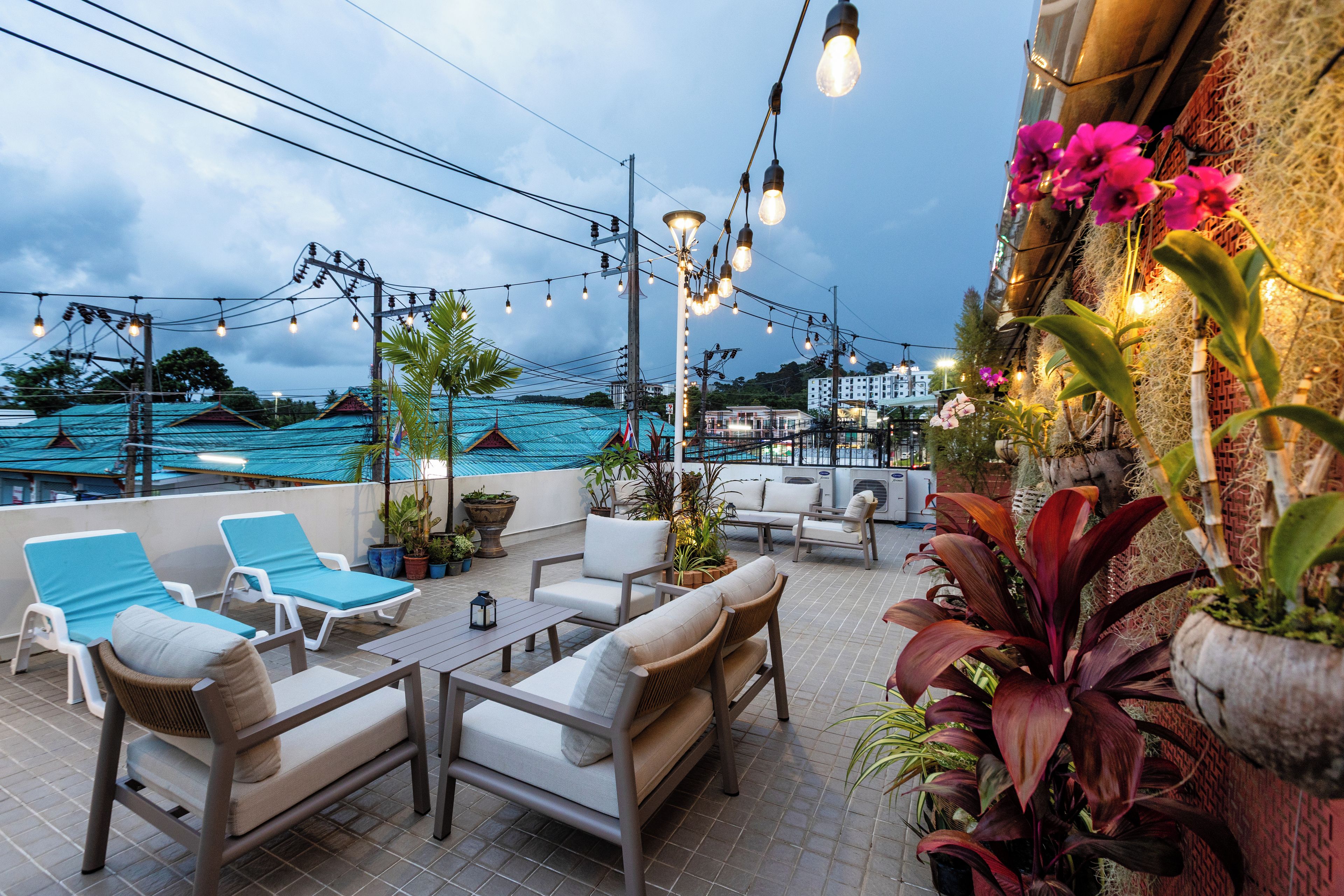 Una terraza en la azotea con asientos al aire libre, luces colgantes y plantas en macetas.