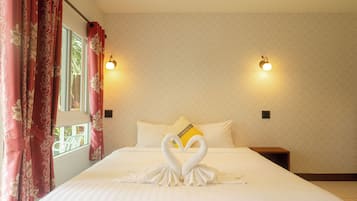 A hotel room with a bed, two wall-mounted lights, a window with curtains, and a geometric-patterned wall.