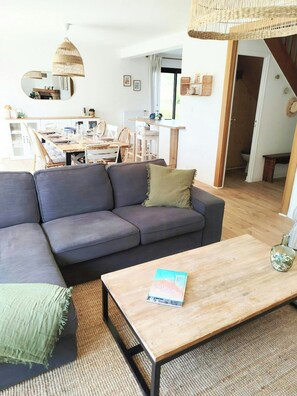 Een woonkamer met een bank, een salontafel en een eethoek met stoelen en een tafel.