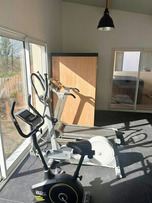 A home gym with an elliptical, a stationary bike, and a treadmill. - House with spa and sauna on the Côte des Sables (Cléder)