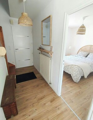 Een slaapkamer met een bed, nachtkastje, spiegel en radiator.