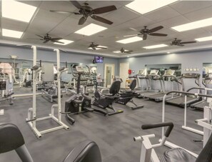 A gym with ceiling fans, exercise equipment, and a television on the wall. - Cozy 1-bedroom condo Branson (Branson)