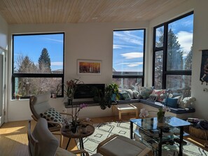 Una sala de estar moderna con ventanas amplias, chimenea y diferentes opciones de asientos.