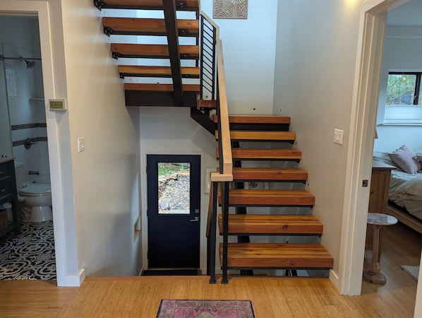 Una escalera de madera con barandillas metálicas que lleva a una puerta.
