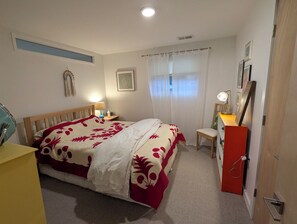 Un dormitorio con cama, mesita de noche, lámpara, silla y escritorio con lámpara.