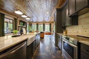 A modern kitchen with wooden ceiling, stainless steel appliances, and a central island. - Broke `n Boujee · New Listing! Heated Pool, Sauna, Arcade & Mini-Golf for 20 (Broken Bow)