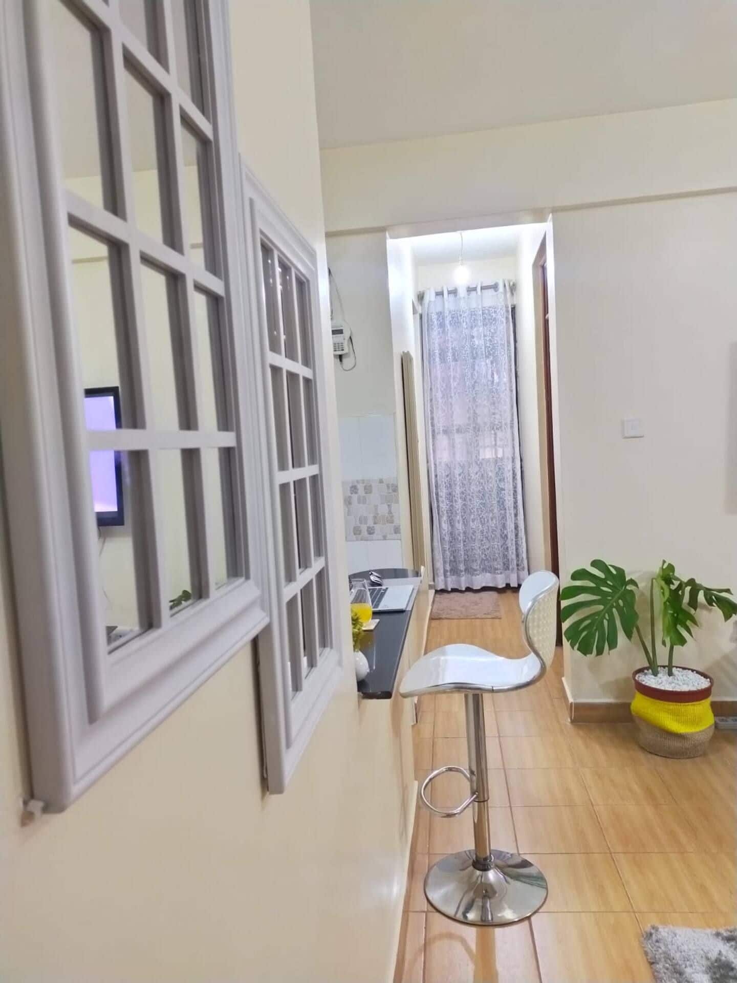 A room with a dining area, a potted plant, and a window with a curtain.