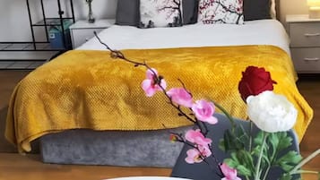 A bedroom with a bed, a bedside table, a nightstand, and a wall-mounted shelf with towels.