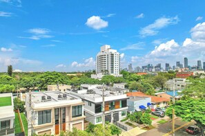 A residential area with modern buildings, a clear sky, and a distant city skyline. - Miura New Modern Miami | Luxury Villa  4BR 10PPL (Miami)