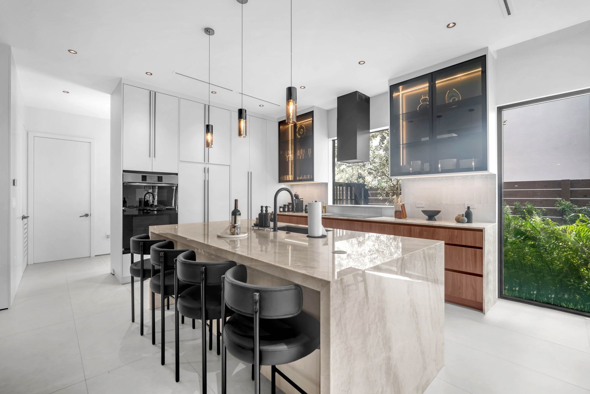 A modern kitchen with a central island, bar stools, and pendant lighting.