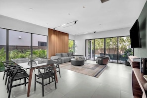 A modern living space with a dining area, a sofa, and a television. - Miura New Modern Miami | Luxury Villa  4BR 10PPL (Miami)