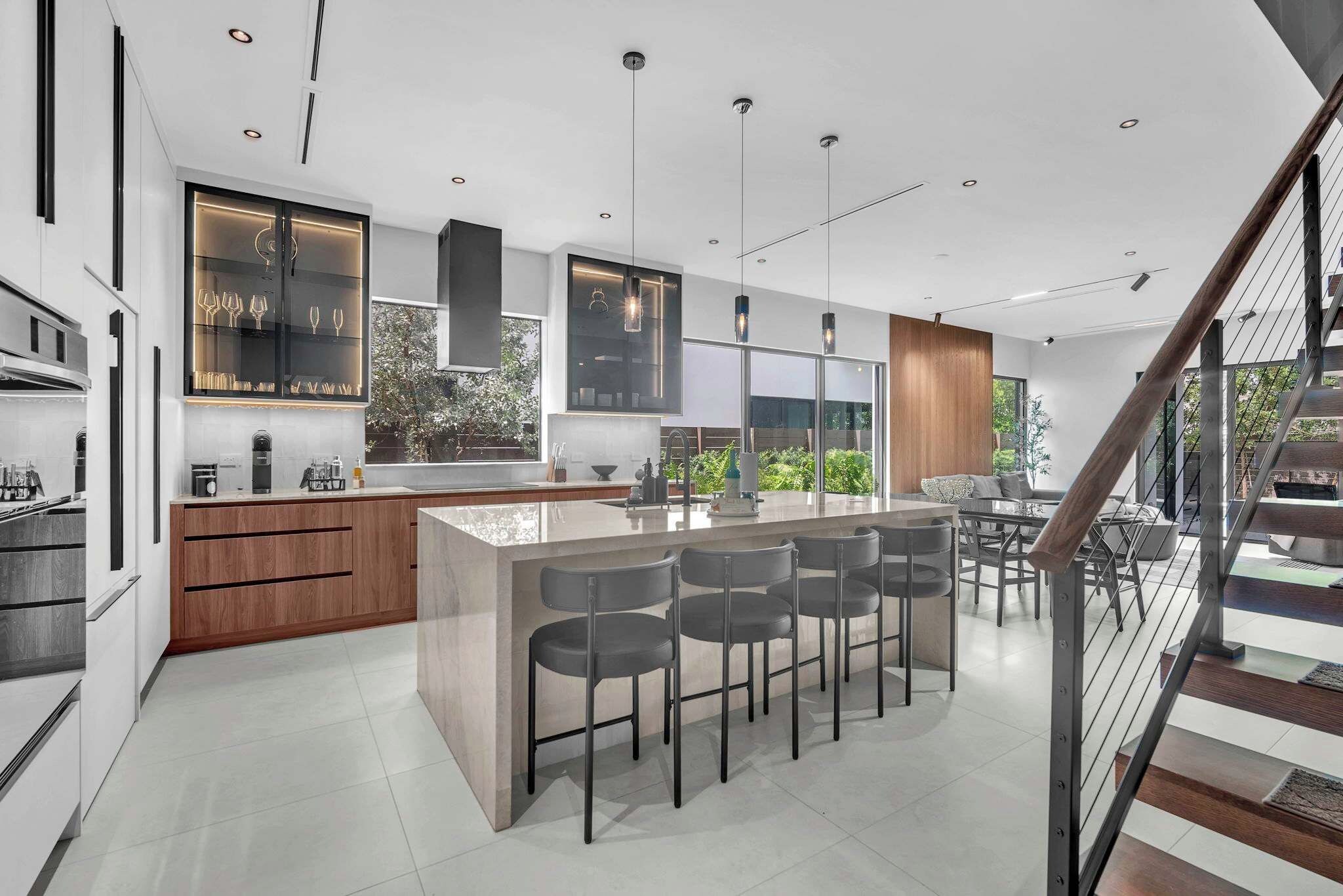 A modern kitchen with a central island, bar stools, and pendant lighting.