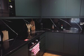 Eine moderne Küche mit dunklen Schränken, einer schwarzen Arbeitsplatte und einer Marmor-Spritzschutzwand.