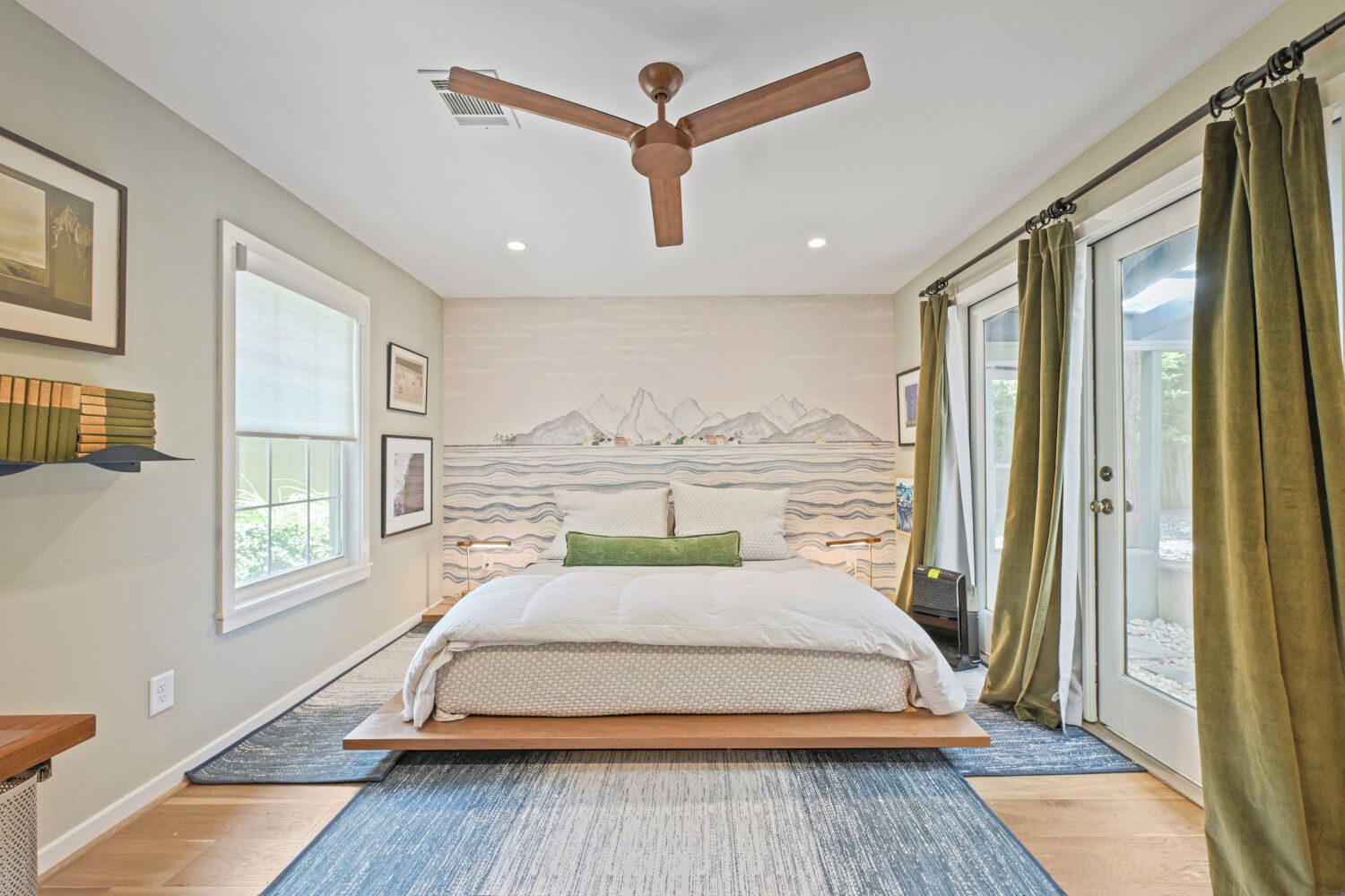 A bedroom with a bed, a ceiling fan, a window, and a view of the outdoors.