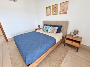Une chambre à coucher avec un lit, des tables de chevet, une lampe et des œuvres d’art murales.