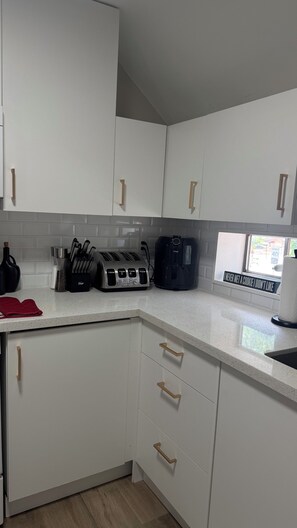 A kitchen with white cabinets, a toaster, a coffee maker, and a window with a sign.