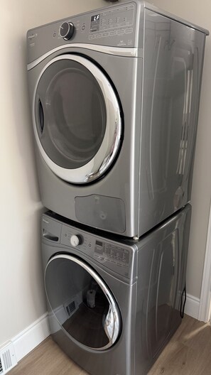 Een gestapelde wasmachine en droger met bedieningspanelen en een digitaal scherm.