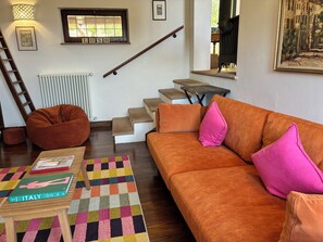 A living room with a sofa, a bean bag, a colorful rug, a book, and a staircase. - Stunning villa with a pool in the Umbria Valley (Gualdo Cattaneo)