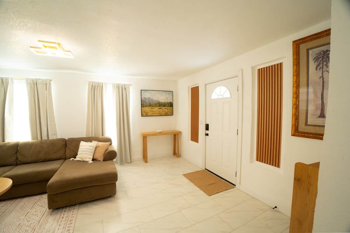 A living room with a sectional sofa, a small table, a door with a window, and a framed picture on the wall.