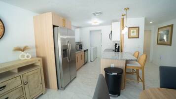 A modern kitchen with a refrigerator, stove, and wooden cabinets.