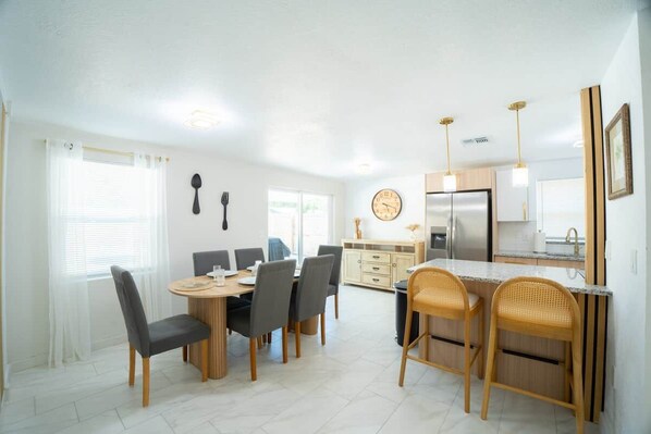 A modern kitchen with a dining area, featuring a round table, chairs, and a built-in island with seating.