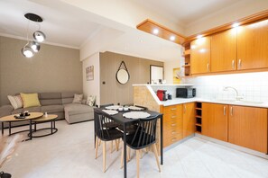 A modern kitchen with wooden cabinets, a dining area with a table and chairs, and a living room with a sofa and a coffee table. - Comfy stay 2br flat 1gbps 4 min walk from metro (Athina)
