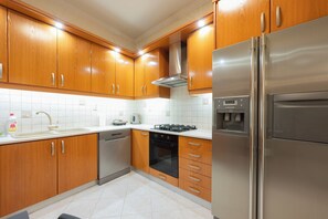 A modern kitchen with wooden cabinets, stainless steel appliances, and a tiled backsplash. - Comfy stay 2br flat 1gbps 4 min walk from metro (Athina)