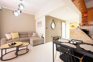 A modern living room with a sofa, coffee table, and dining area with chairs and a table. - Comfy stay 2br flat 1gbps 4 min walk from metro (Athina)