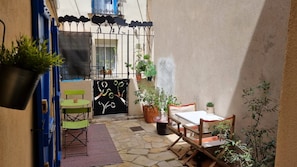 An outdoor patio with a table and chairs, a gate, and potted plants. - Le sétois 2, intimiste et cosy (Sète)