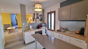 Una cocina moderna con una isla central, electrodomésticos integrados y un ventanal con contraventanas de madera.