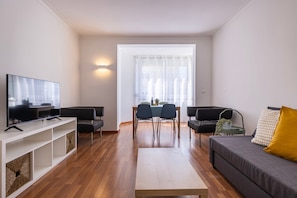 Un salon moderne doté d’un téléviseur à écran plat, d’un canapé, d’une table basse et d’un coin repas avec des chaises et une table.