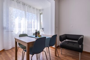 Un coin repas avec une table en bois, quatre chaises, une bouteille de vin et une petite plante en pot.