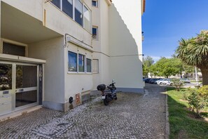A building with a paved courtyard, a parked scooter, and a clear blue sky. - Apartment 'Lisbon Oceanside' (Carcavelos)