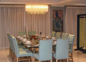 Comedor con una larga mesa dispuesta para seis personas, rodeada de sillas tapizadas con detalles de botones.