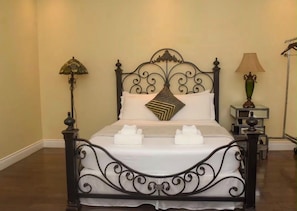 Una cama con un cabecero decorativo, dos lámparas de noche y una mesita de noche con lámpara.