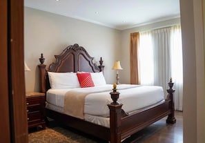Een hotelkamer met een groot bed, een houten hoofdbord, nachtkastjes en een raam met gordijnen.