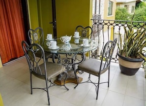 Een ronde glazen tafel met stoelen, een potplant en een deur op de achtergrond.