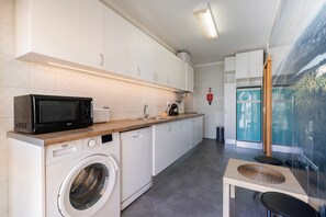 Eine kleine Küche mit Mikrowelle, Waschmaschine und einem Tisch mit einer gewebten Tischmatte.