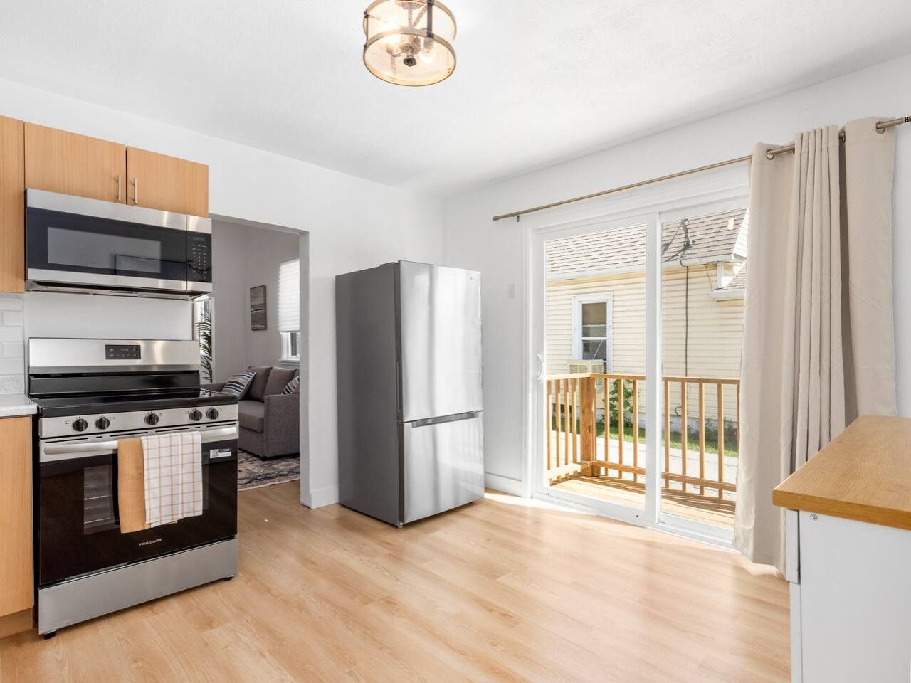Eine moderne Küche mit Edelstahlgeräten, Holzboden und einer Schiebeglastür zum Balkon.