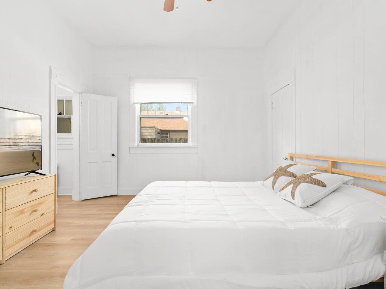 Ein Schlafzimmer mit einem Bett, einer hölzernen Kommode und einem Fernseher.