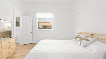 Ein Schlafzimmer mit einem Bett, einer hölzernen Kommode und einem Fernseher.