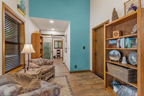 A cozy living room with a sofa, a lamp, and a bookshelf filled with books and decorative items. - NEW! | Rustic Woodland Retreat | Pets | Fireplace (Flagstaff)