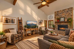 A cozy living room with a fireplace, wooden furniture, and a large painting of a mountain. - NEW! | Rustic Woodland Retreat | Pets | Fireplace (Flagstaff)
