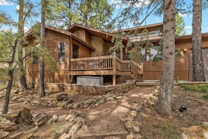 A cabin with a wooden deck, stone walls, and a stone fireplace. - NEW! | Rustic Woodland Retreat | Pets | Fireplace (Flagstaff)