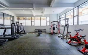 Une salle de sport équipée de tapis de course, d’un vélo d’appartement et de matériel de musculation.