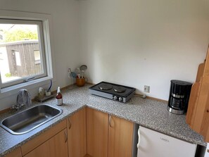 A compact kitchen with a sink, stove, coffee maker, and wooden cabinets. - 4 Star Holiday Home in Allinge (Allinge)