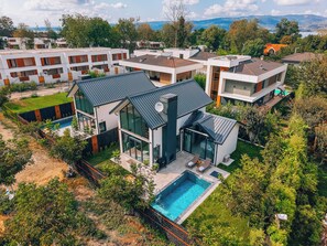 A modern residential complex with multiple houses, a swimming pool, and a view of the surrounding landscape.