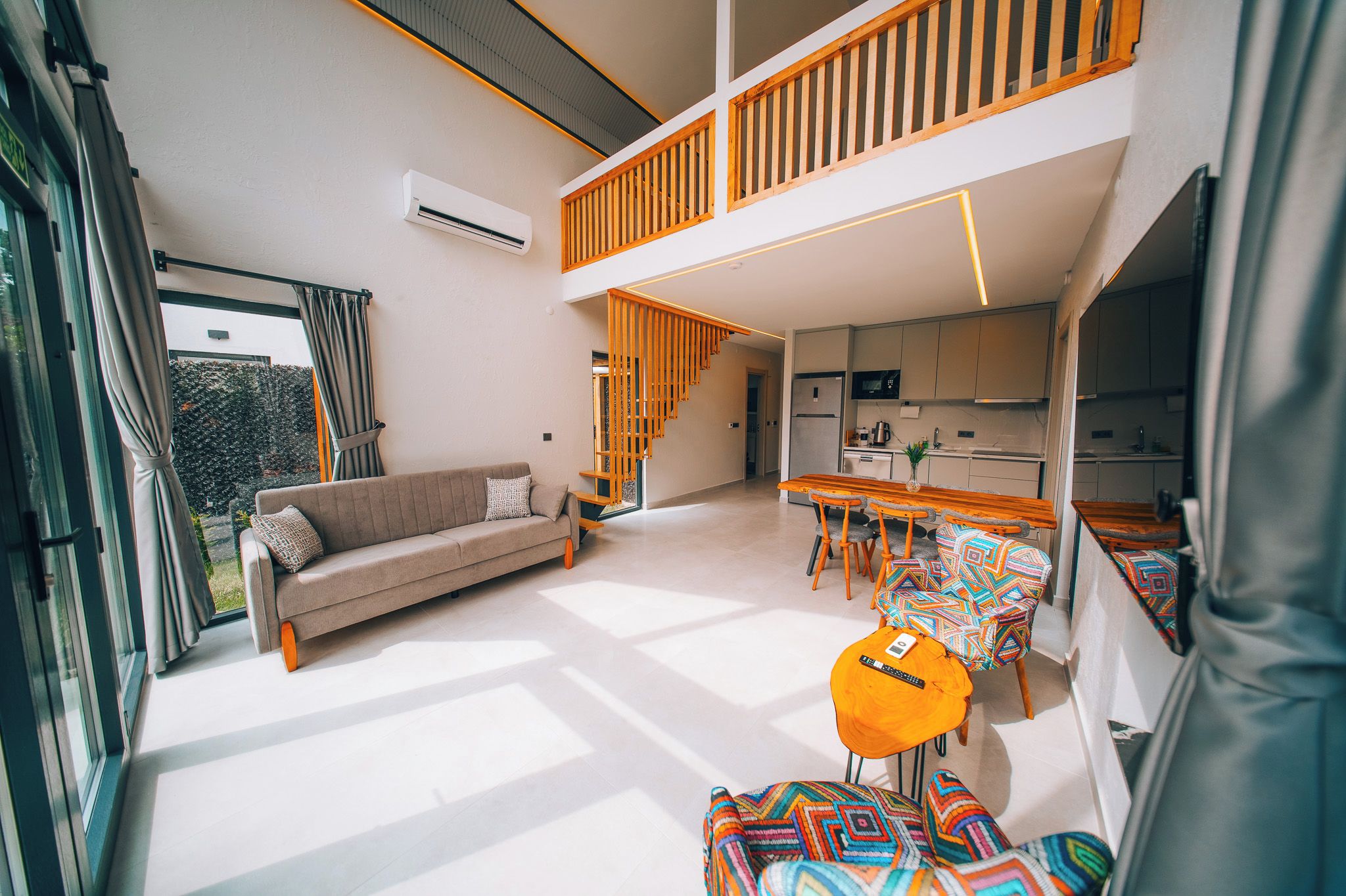 A modern interior with a sofa, dining table, and chairs, a kitchen area, and a staircase.