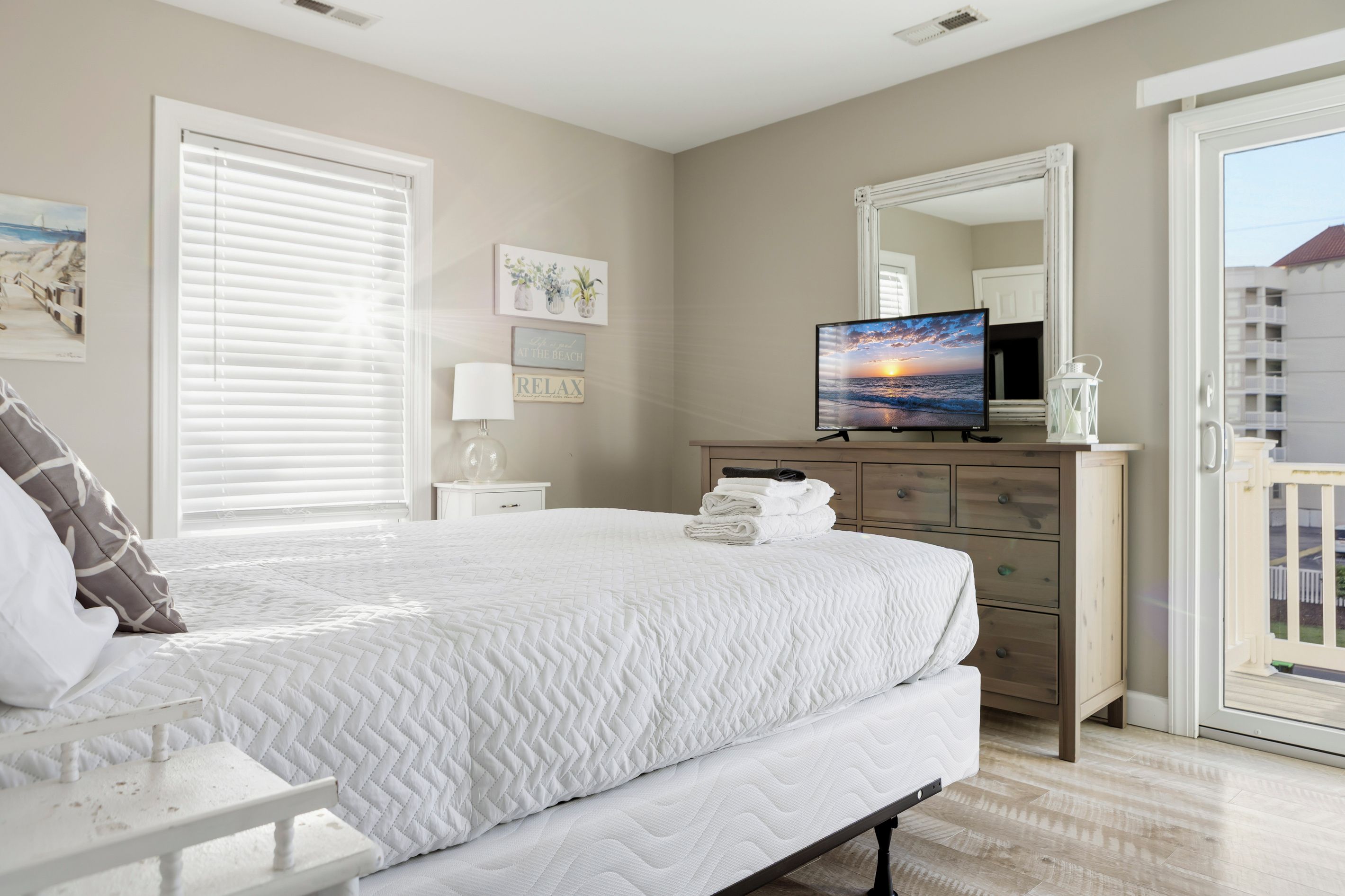 Un dormitorio con cama, cómoda, televisor y ventana con persianas.