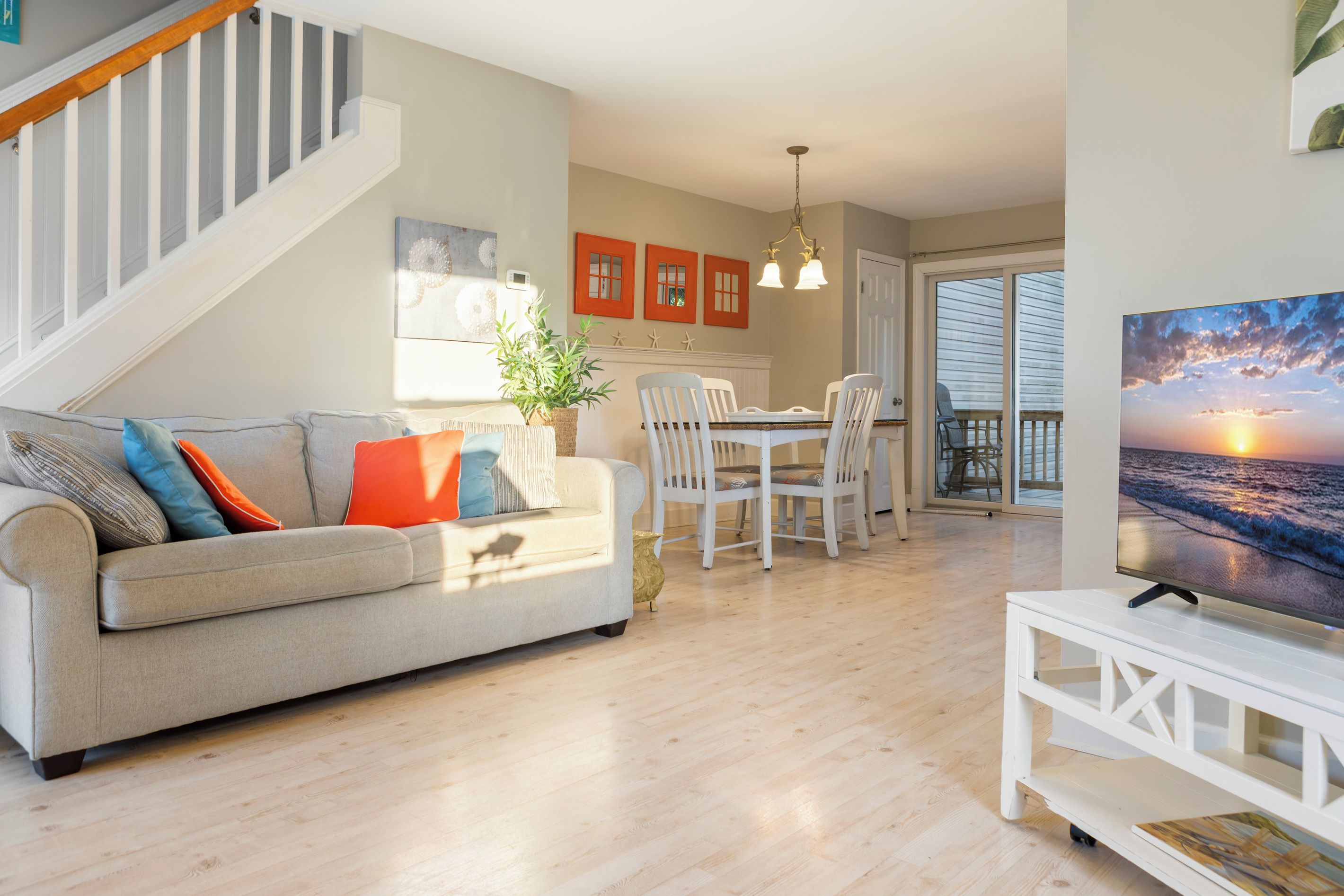 A living room with a sofa, dining table, chairs, a TV, and a staircase.